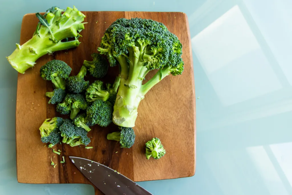 Pieces of Broccoli in cutting board with knife