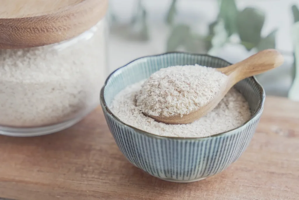 Psyllium husk in wooden spoon and bowl on wooden plate