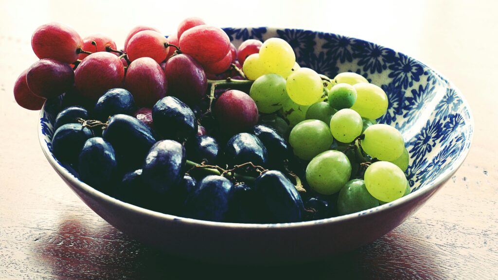 green, red, and black grapes in a bowl