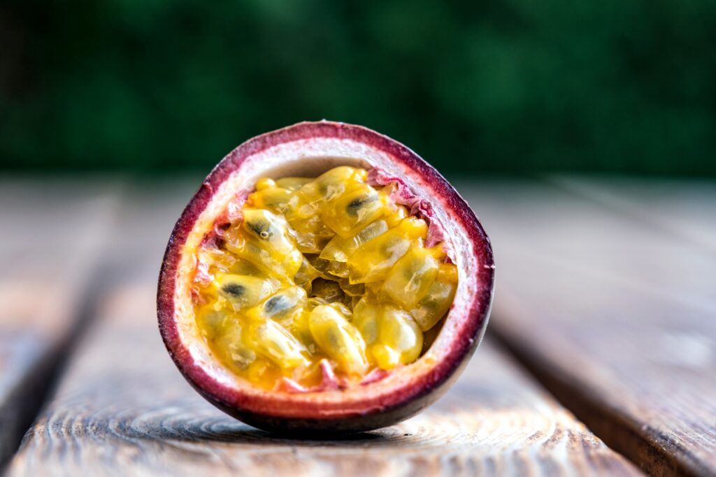 Half-cut passion fruit placed on a wooden desk, showing its juicy, seed-filled interior.